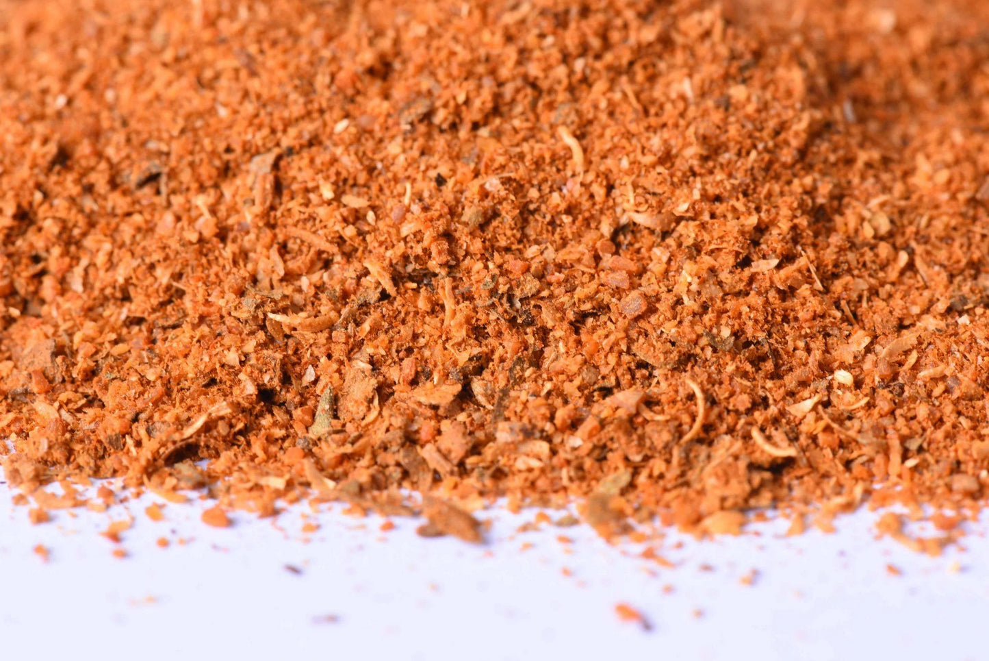 Close-up of a vibrant orange spice blend mix, finely ground for cooking and grilling.