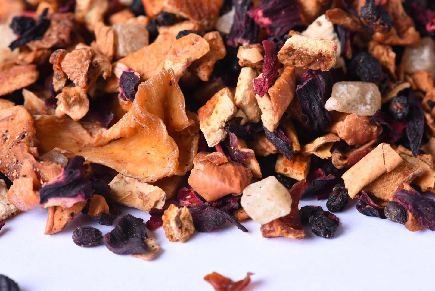 Loose leaf gourmet tea blend with dried fruit, hibiscus, and spice pieces close-up