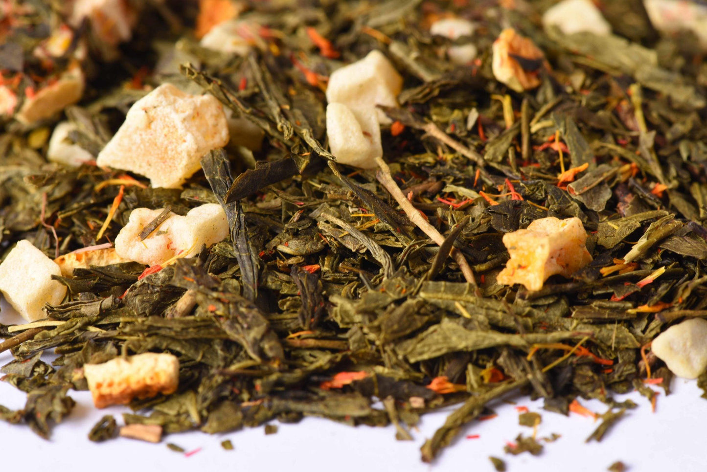 Loose-leaf green tea blend with dried fruit pieces and colorful botanicals