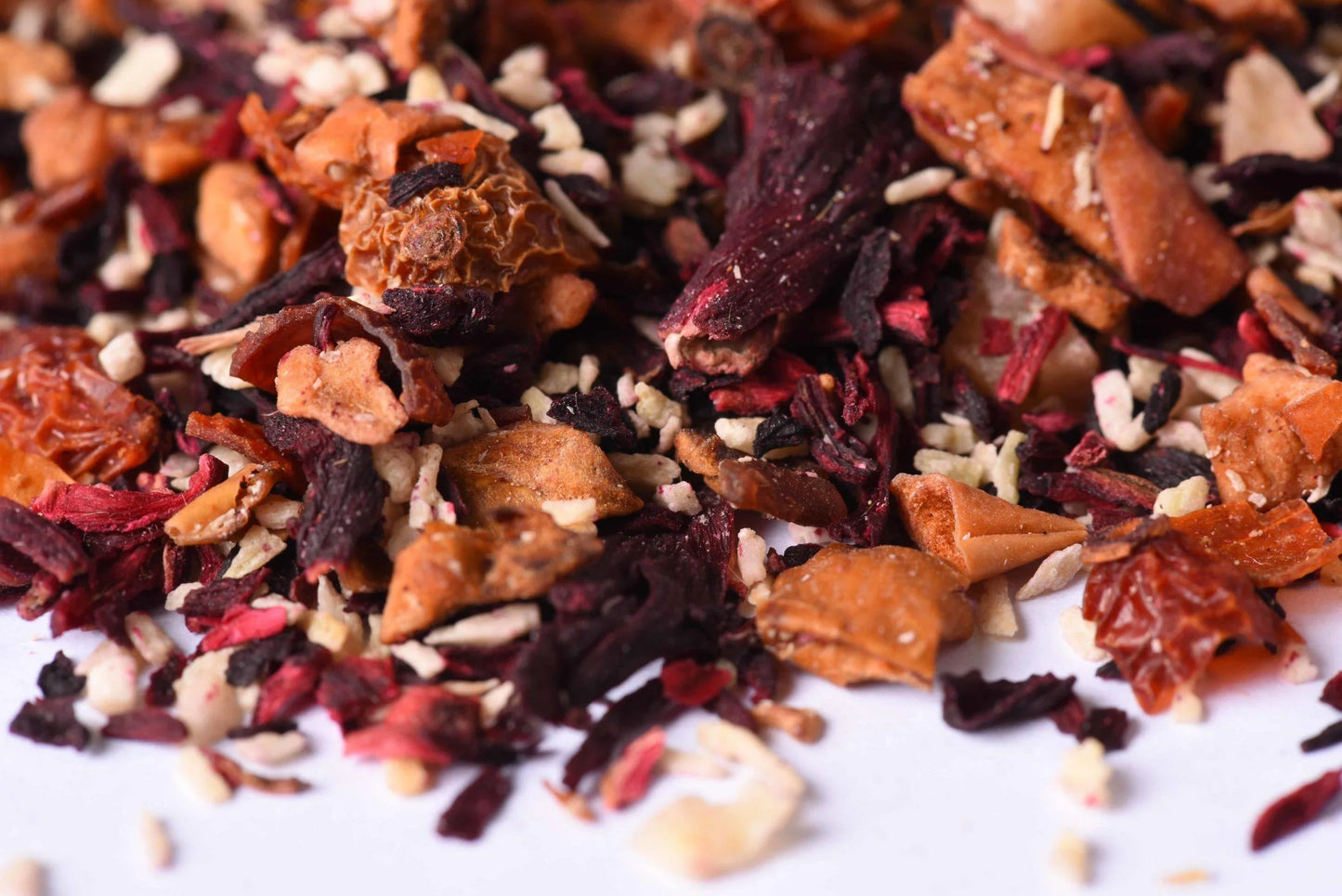 Loose leaf fruit tea blend with dried hibiscus, apple pieces, and orange peel close up