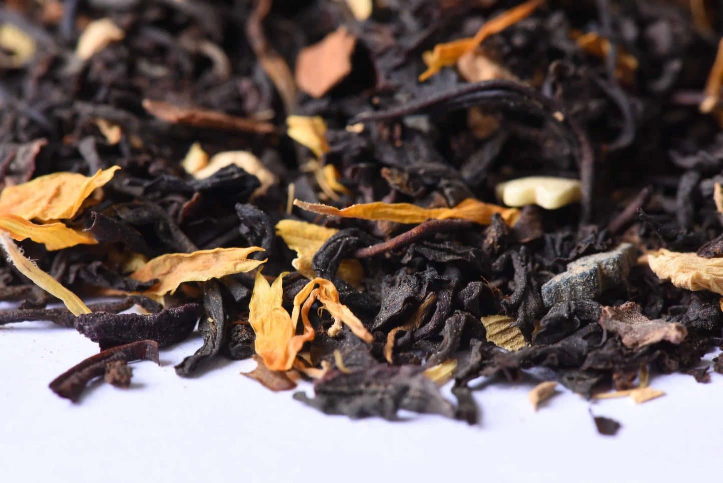 Loose-leaf black tea blend with dried flower petals on white background