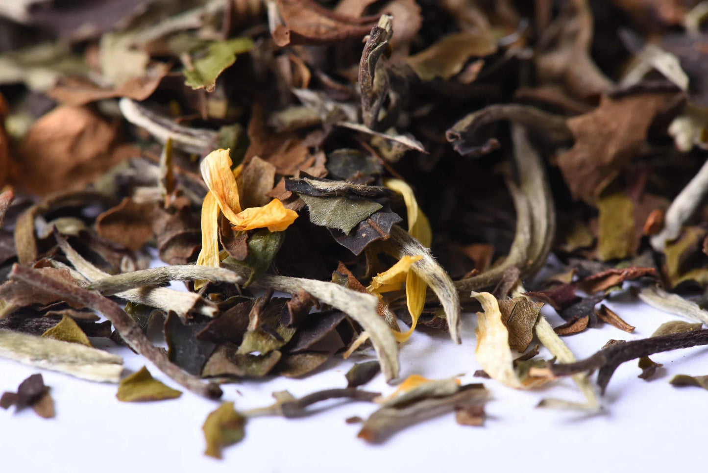 Loose-leaf white tea blend with dried petals and whole leaves close-up