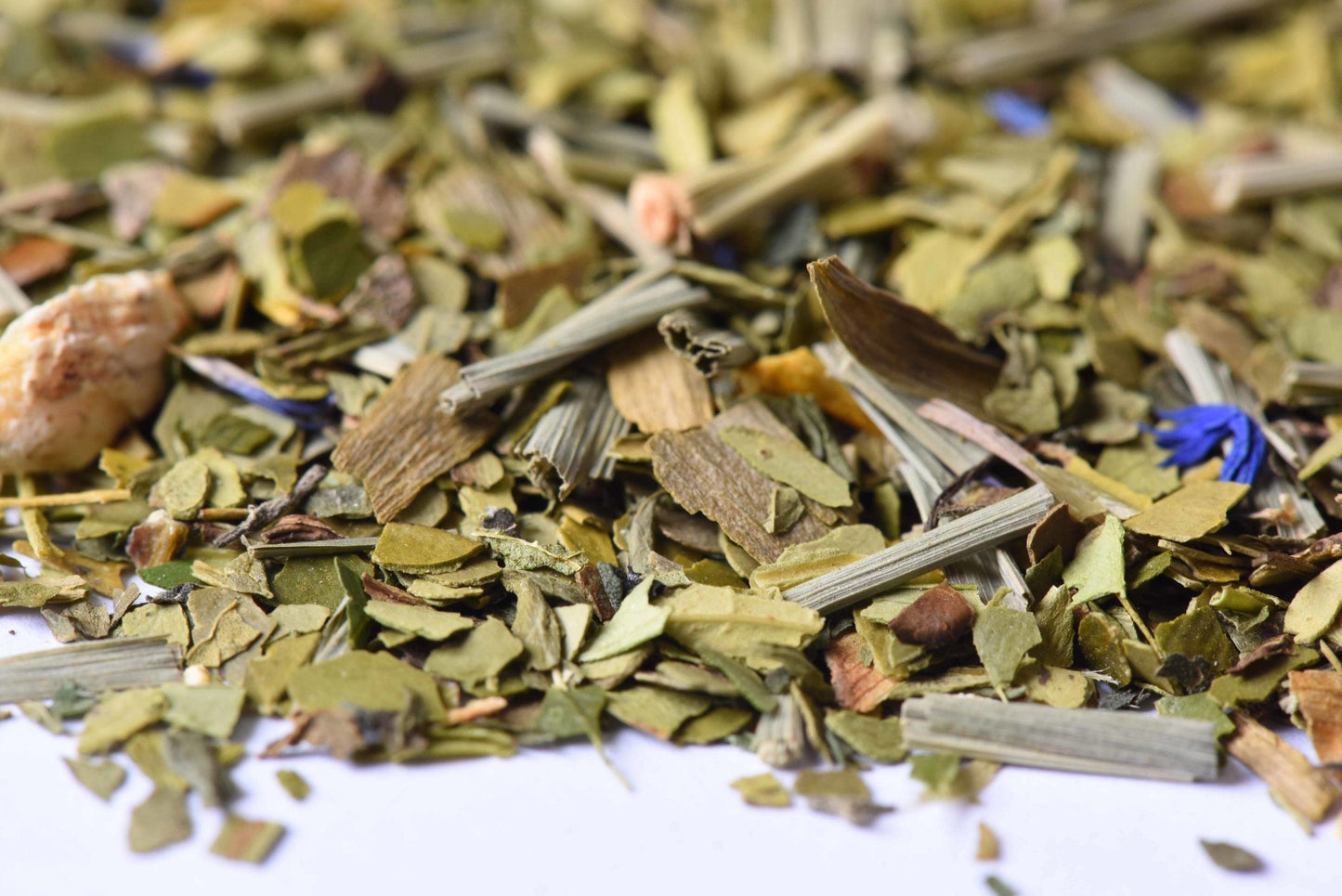 Loose-leaf herbal tea blend with lemongrass, green leaves, and blue petals close-up