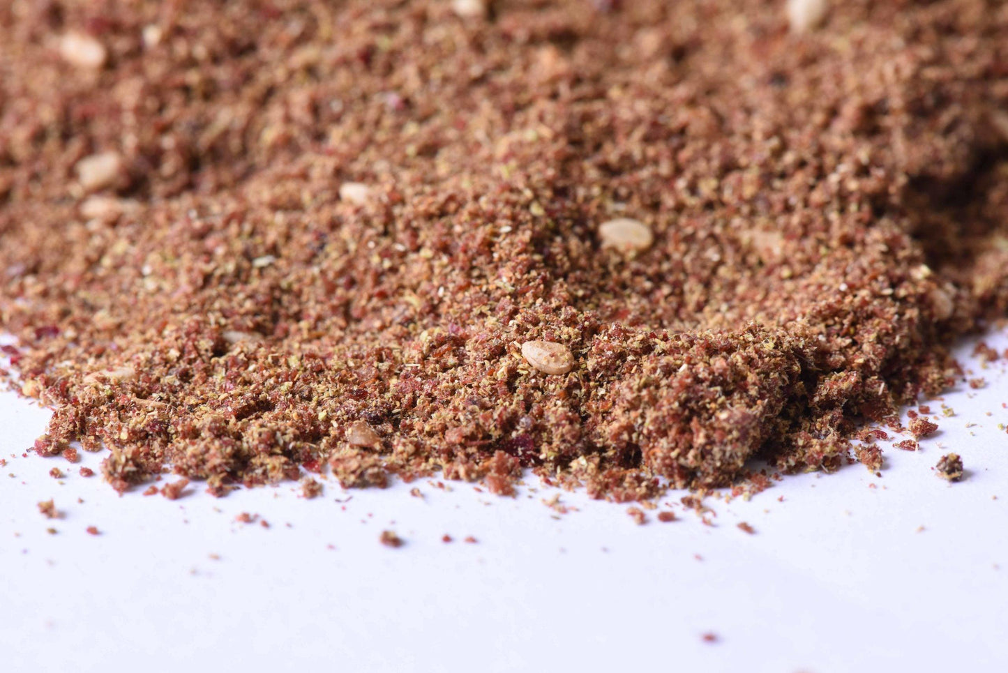 Close-up of a gourmet spice blend with visible sesame seeds on a white surface