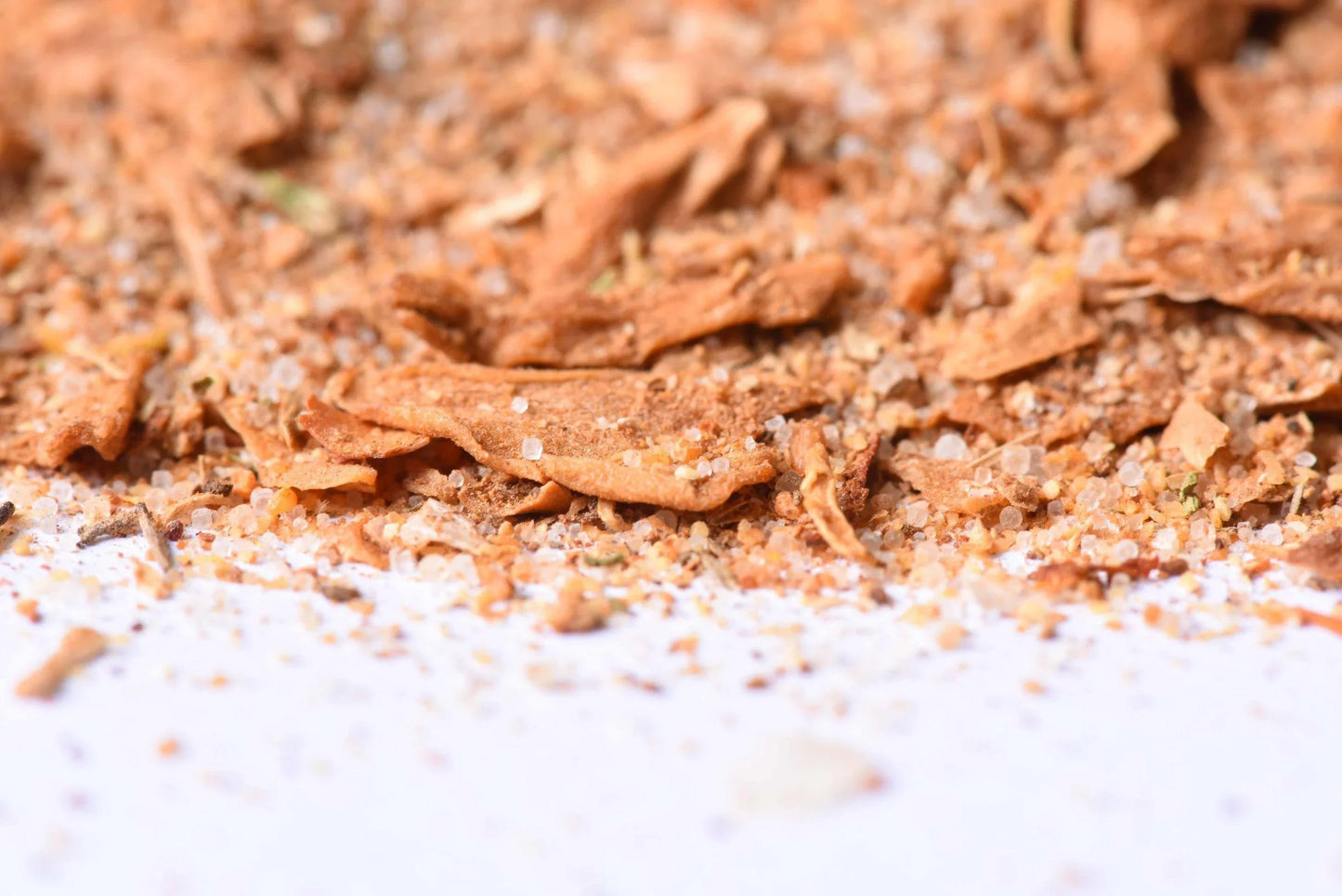 Close-up of gourmet spice blend with herbs and coarse salt on a white surface