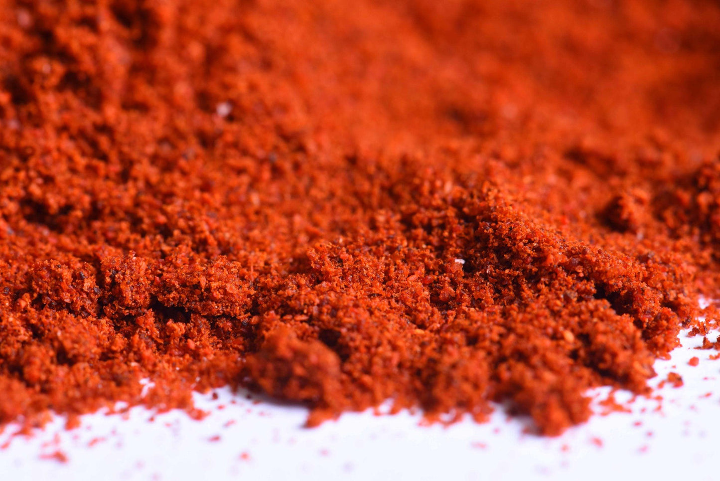 Closeup of vibrant ground red spice blend on a white surface