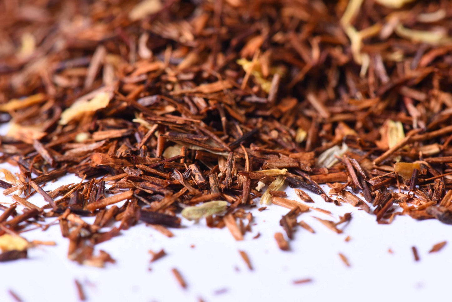 Close-up of loose-leaf rooibos herbal tea blend with dried ingredients on white surface