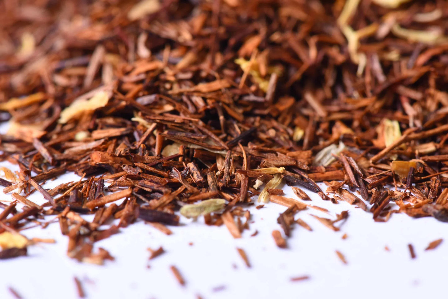 Close-up of loose-leaf rooibos herbal tea blend with dried ingredients on white surface