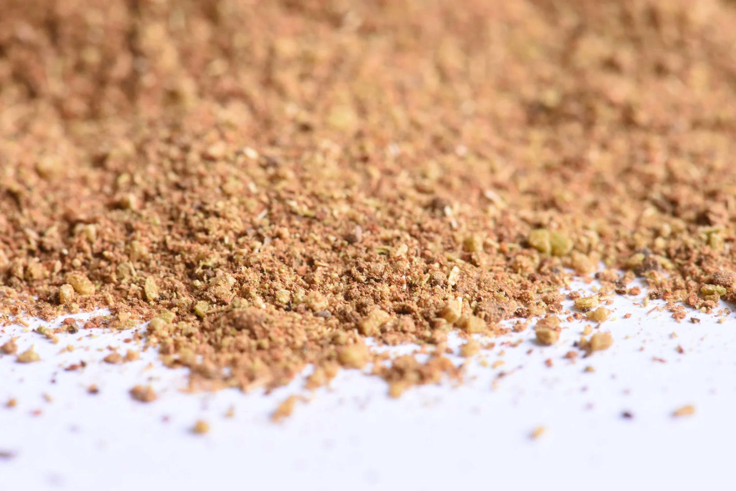 Close-up of powdered spice blend scattered on a white surface