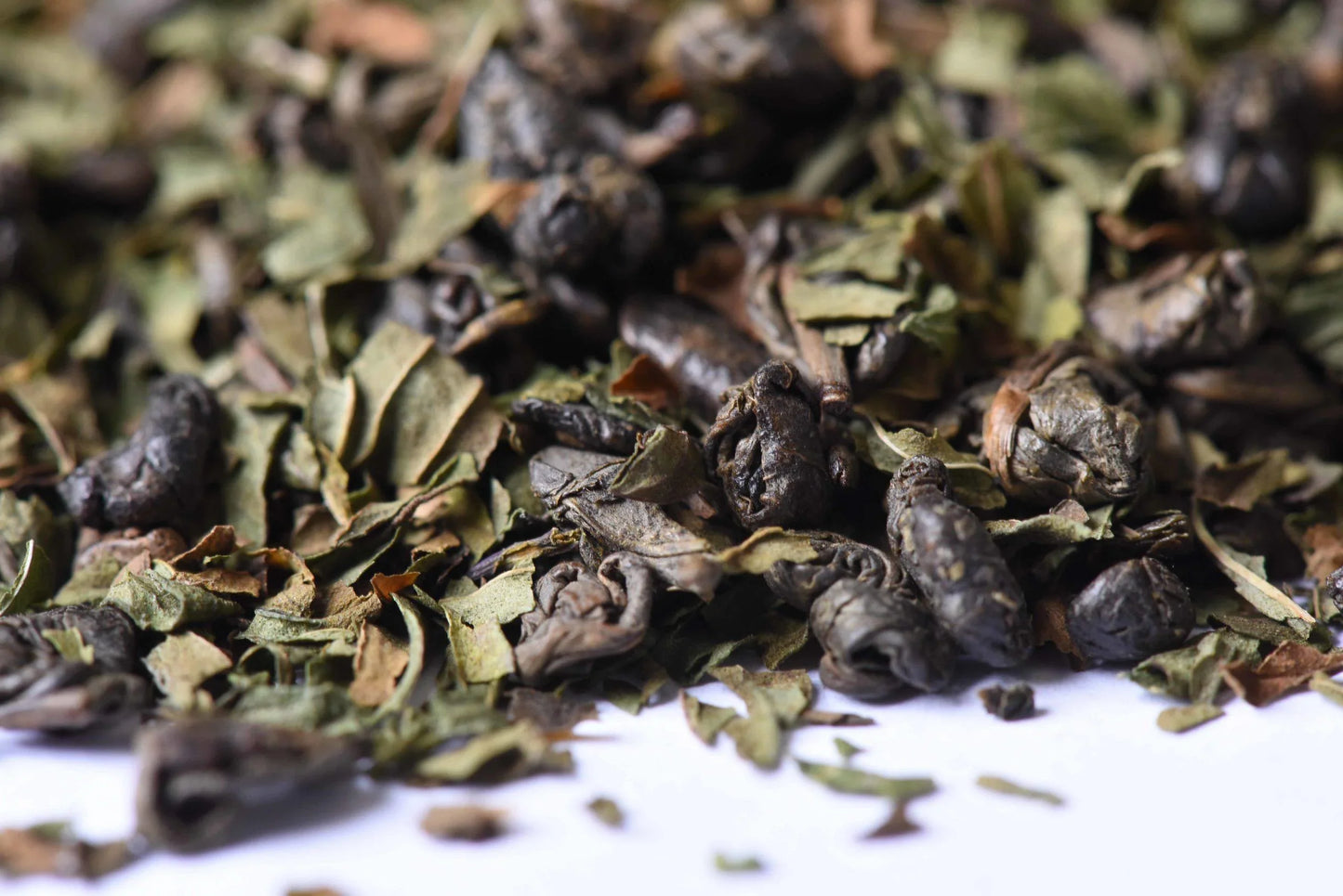 Close-up of loose leaf green tea mixed with dried mint leaves on a white background