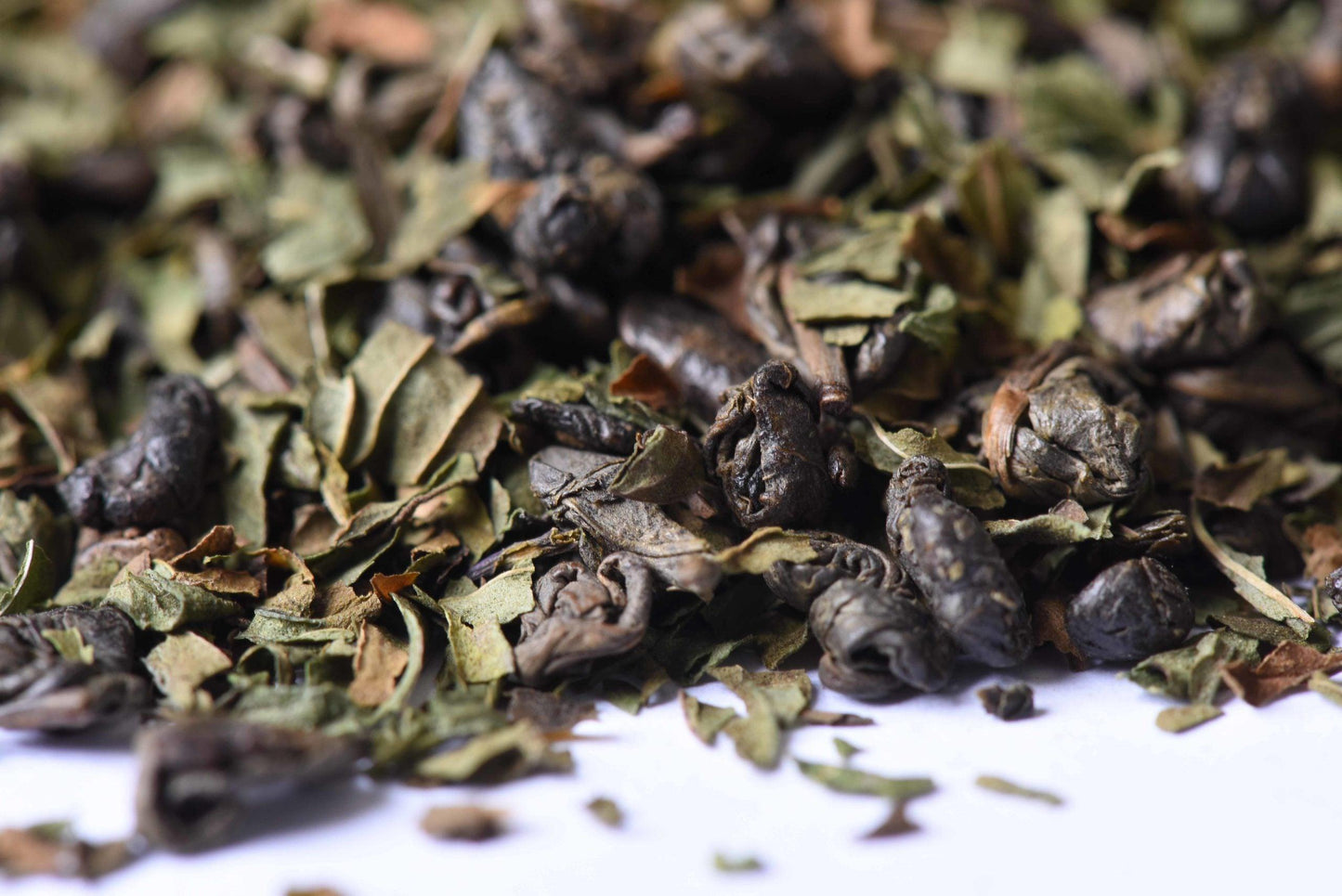 Close-up of loose leaf green tea mixed with dried mint leaves on a white background