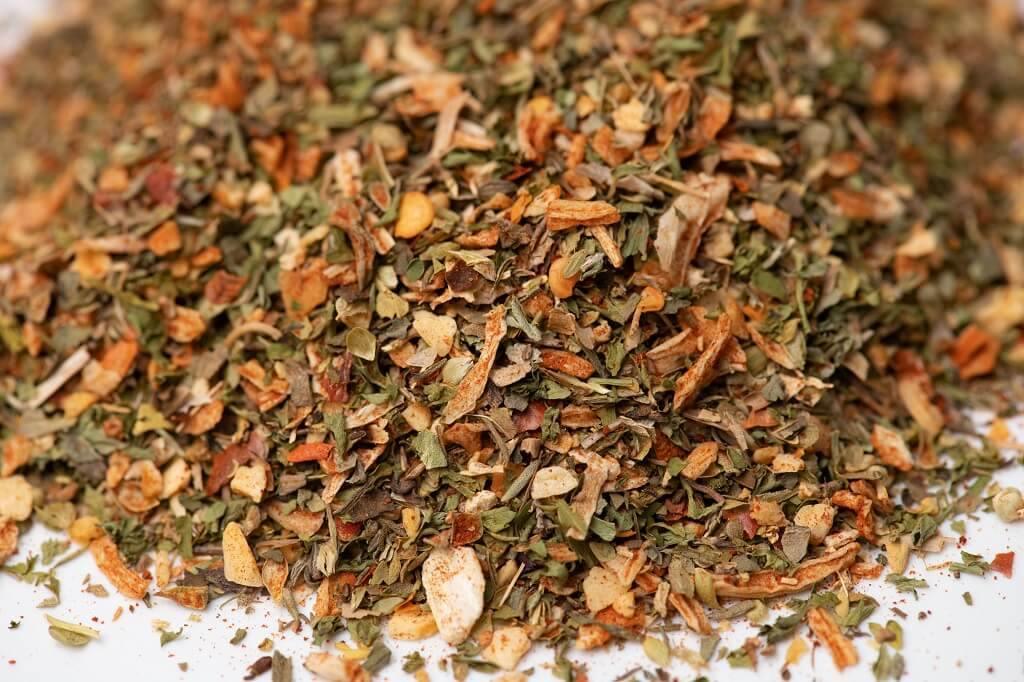 Close-up of mixed dried herbs and spices blend on a white surface