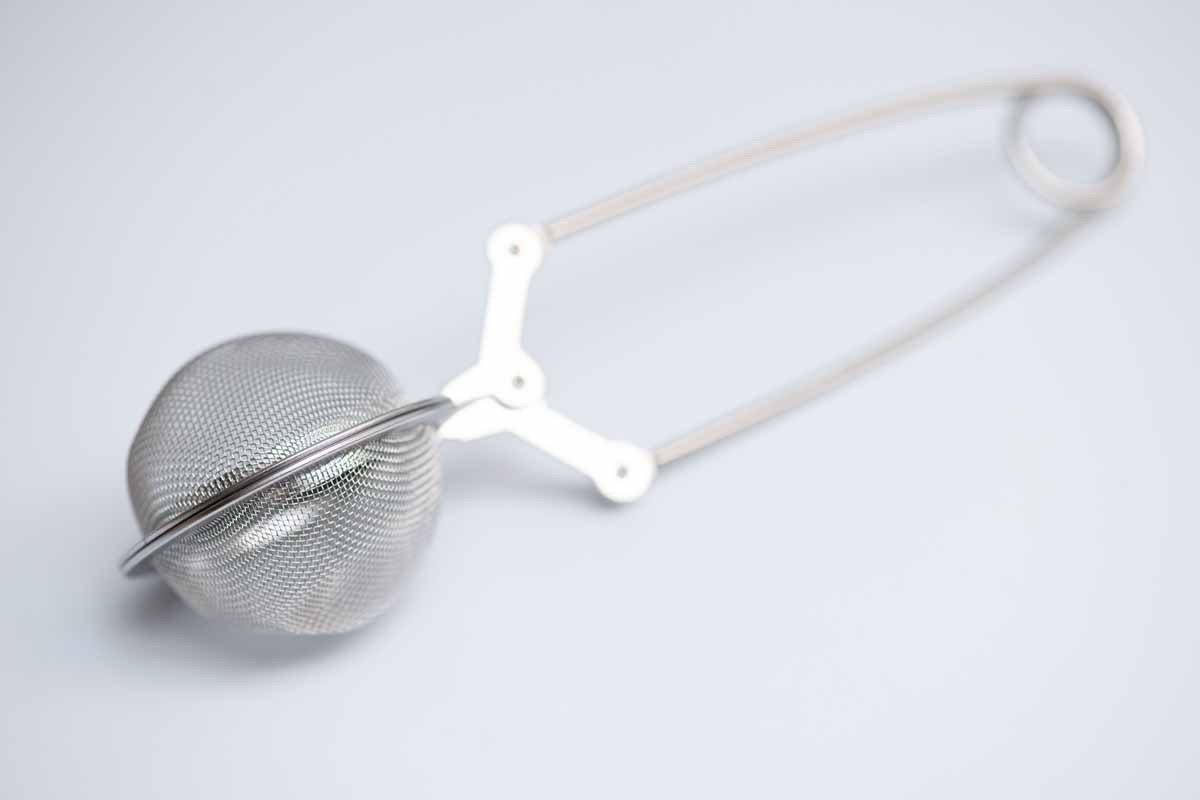 Stainless steel mesh tea infuser ball with handle on white background