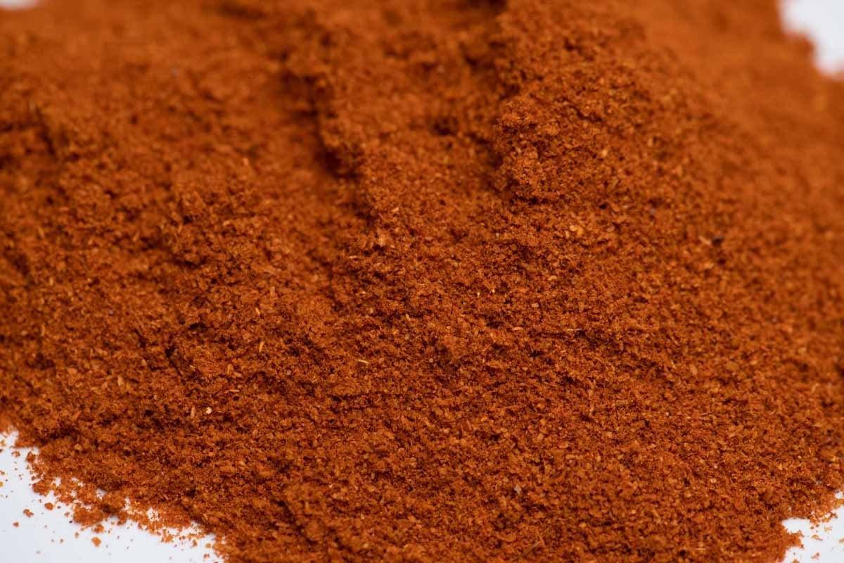Close-up of fresh, ground red spice blend seasoning on a white background