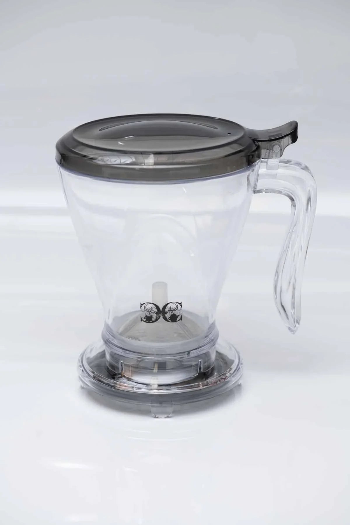 Clear plastic loose-leaf tea infuser with handle and black lid on white background