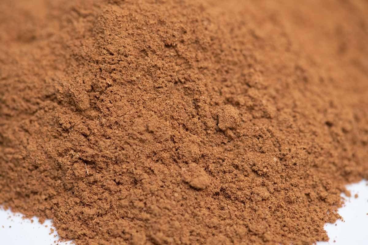 Close-up of ground brown spice powder blend on white background