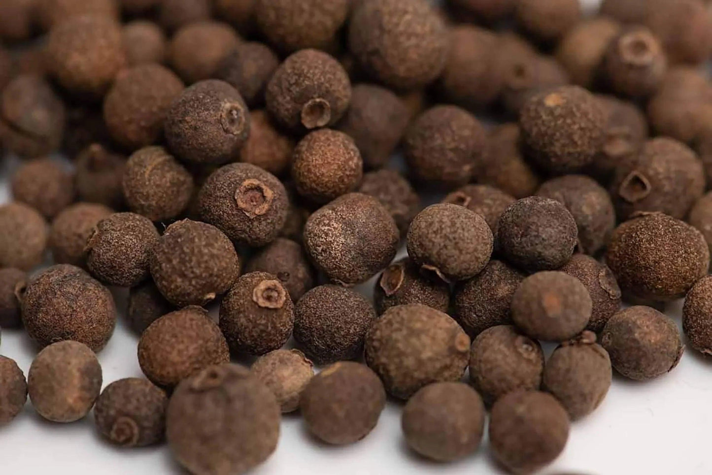Whole dried allspice berries close up, aromatic spice for cooking and seasoning.