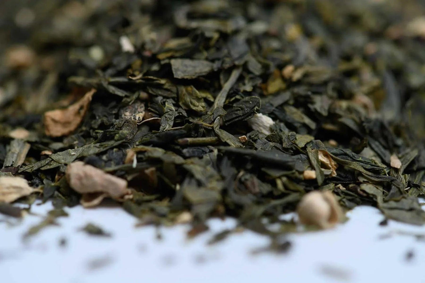 Loose leaf green tea blend with dried ginger and herbs close-up