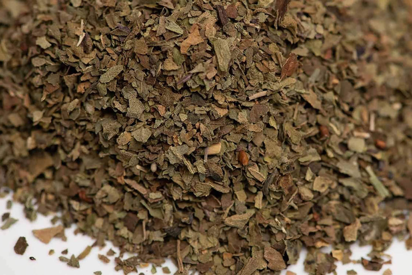 Close-up of dried loose-leaf herbal tea blend with finely chopped green and brown leaves
