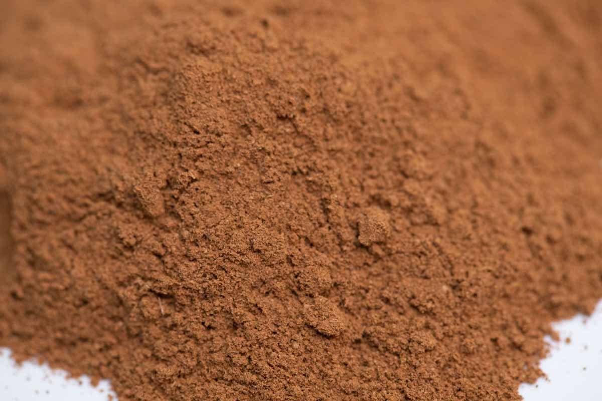 Close-up of finely ground cinnamon spice powder on a white surface