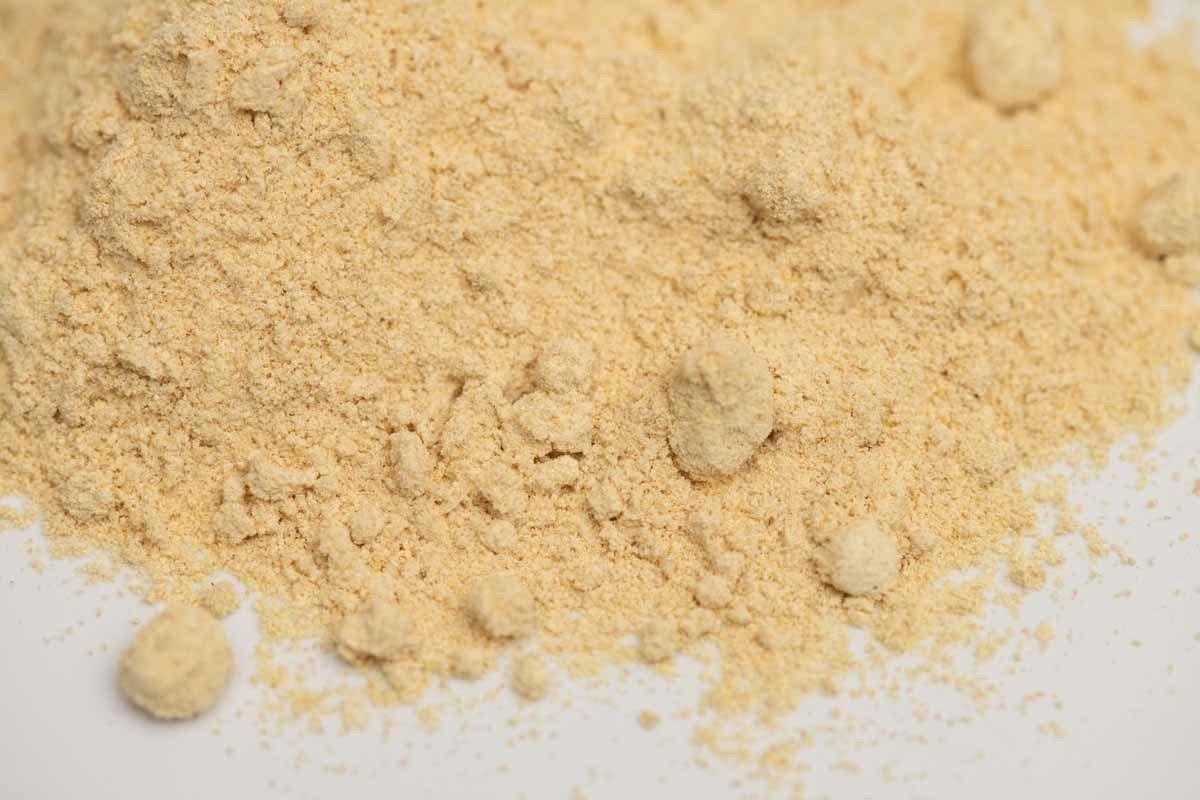 Close-up of ground ginger powder spice on a white background, fine texture, golden color.