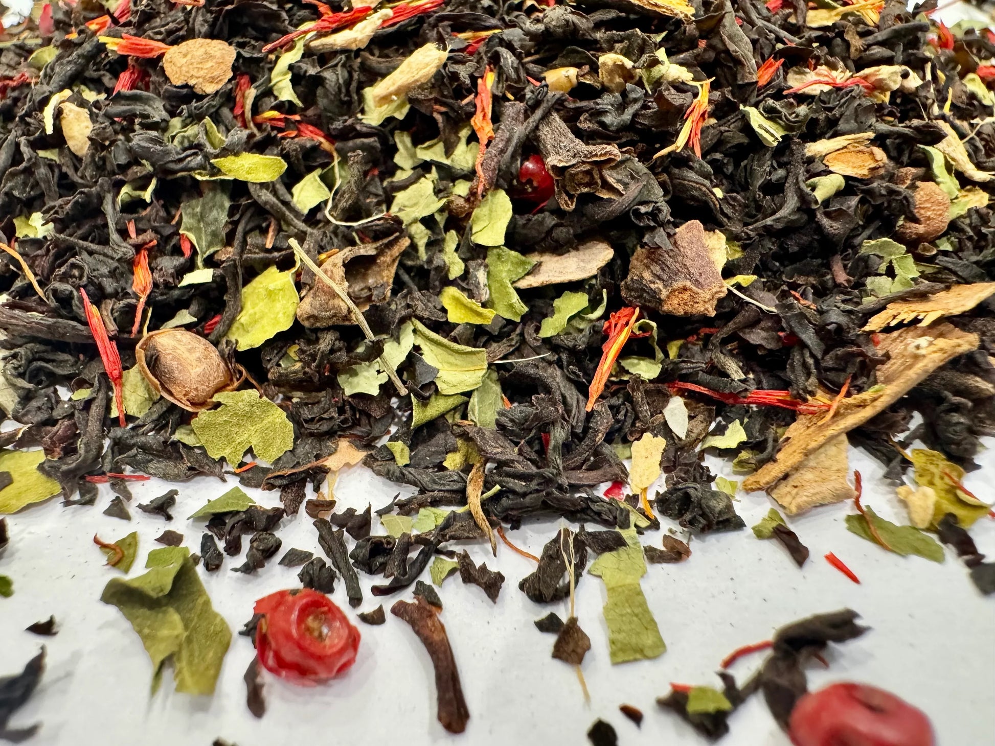 Assorted loose leaf tea with visible spices on a white background