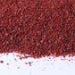 Close-up of coarse ground red sumac spice on white background for cooking and seasoning.