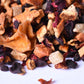 Loose leaf gourmet tea blend with dried fruit, hibiscus, and spice pieces close-up
