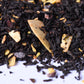 Loose-leaf black tea blend with dried fruit and nut pieces on a white surface