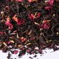 Loose leaf black tea blend with dried rose petals and spices on a white background