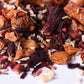 Loose leaf fruit tea blend with dried hibiscus, apple pieces, and orange peel close up