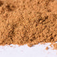 Close-up of a pile of ground spice blend, brown gourmet seasoning powder on white surface
