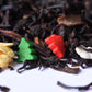 Loose-leaf black tea with festive holiday sprinkles and a yellow flower petal