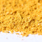 Close-up of bright yellow ground spice blend on a white surface