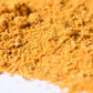 Close-up of yellow spice blend powder with fine and coarse texture on a white background.