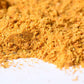 Close-up of golden yellow gourmet spice blend powder on a white surface
