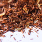 Close-up of loose-leaf rooibos herbal tea blend with dried ingredients on white surface