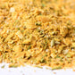 Close-up of a yellow gourmet spice blend with visible herbs and coarse salt granules