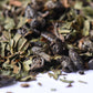 Close-up of loose leaf green tea mixed with dried mint leaves on a white background