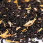 Loose-leaf black tea blend with dried yellow flower petals, close-up view