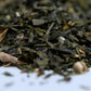 Loose leaf green tea blend with dried ginger and herbs close-up